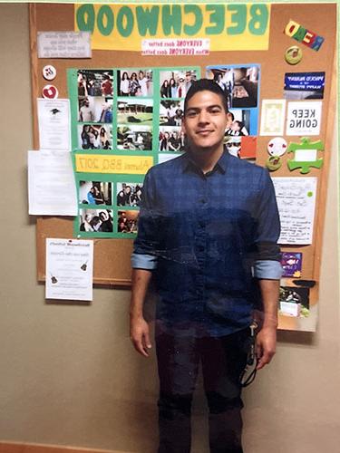 Man alum standing in front of Beechwood bulletin board